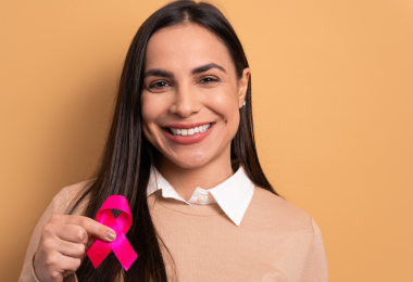 Frau zeigt rosa Schleife zur Aufmerksamkeit für Brustkrebs.