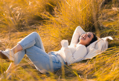 Frau liegt fröhlich im Gras.
